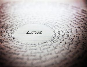 the word love written on a lined piece of school paper in ink wi