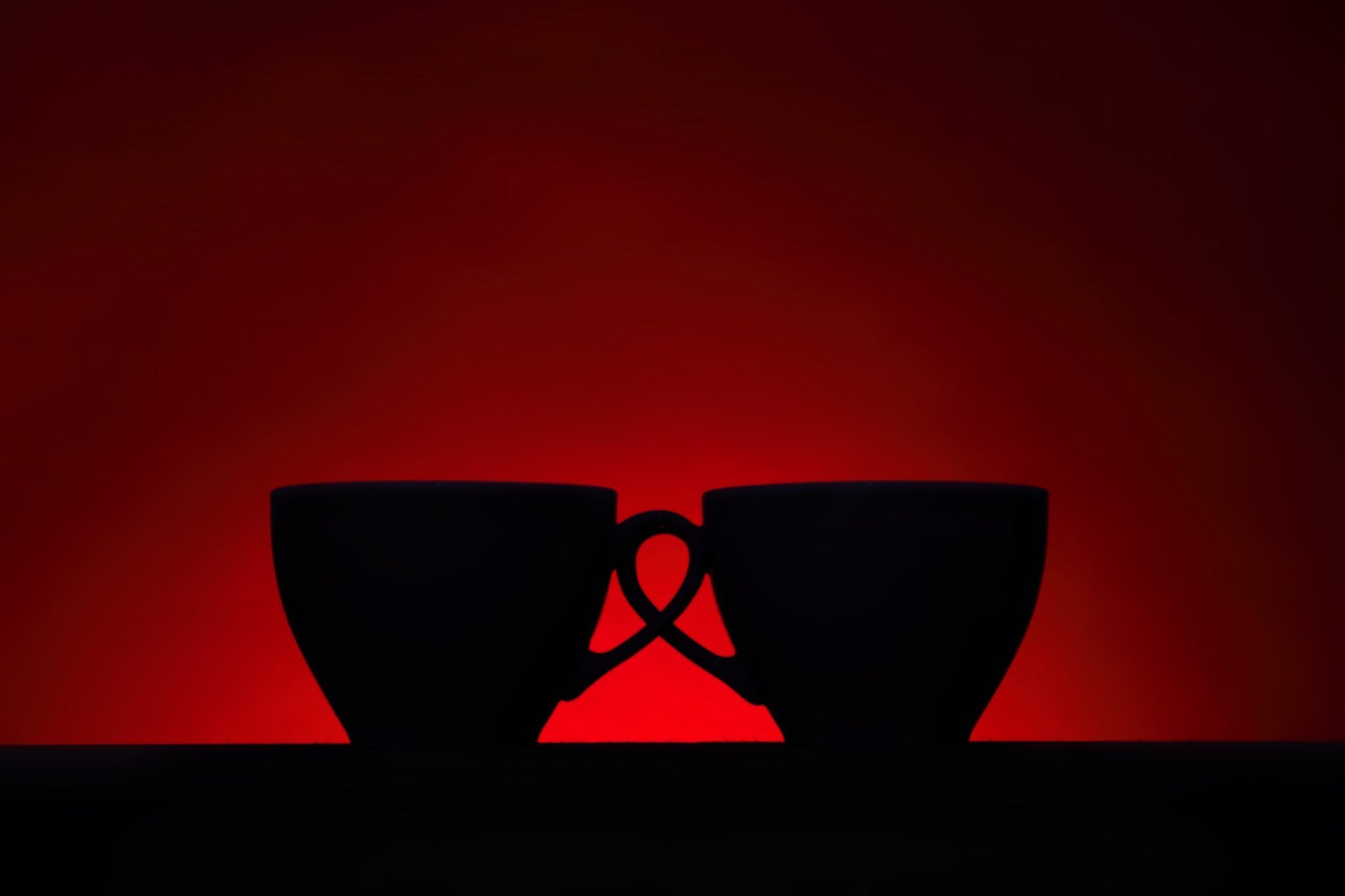 Silhouettes of two coffee cups on red background
