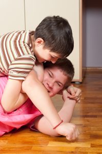 Two teenage boys wrestling on wooden floor