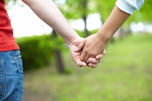 Close-up of female and male holding by hands in park